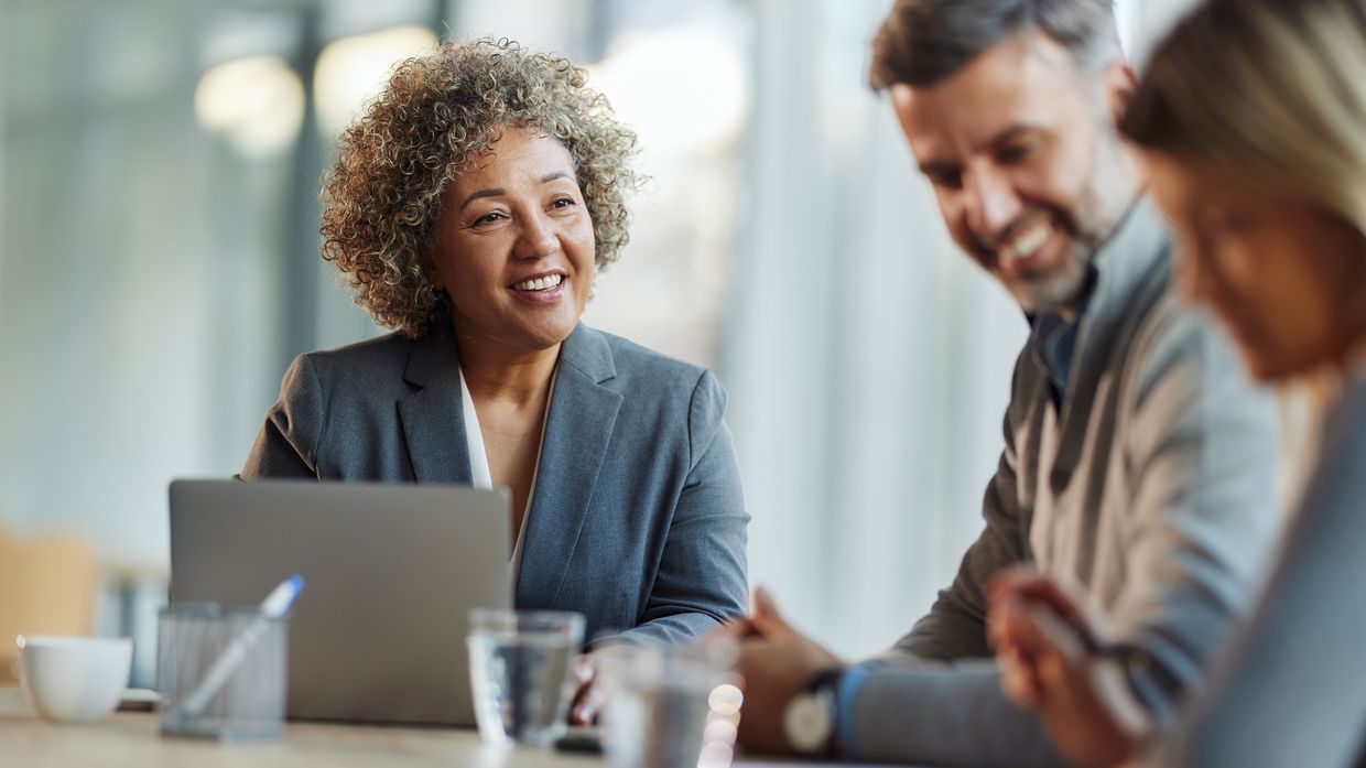 Happy female agent communicating with a couple during a meeting in the office. Copy space.