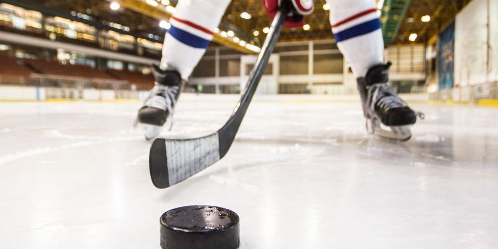 Close-up of hockey player's skates, stick and puck on ice
