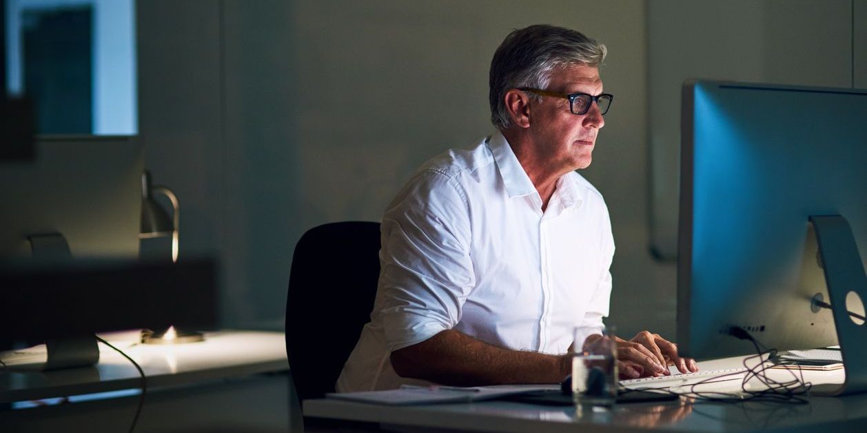 Shot of a mature businessman working late on a computer in an office