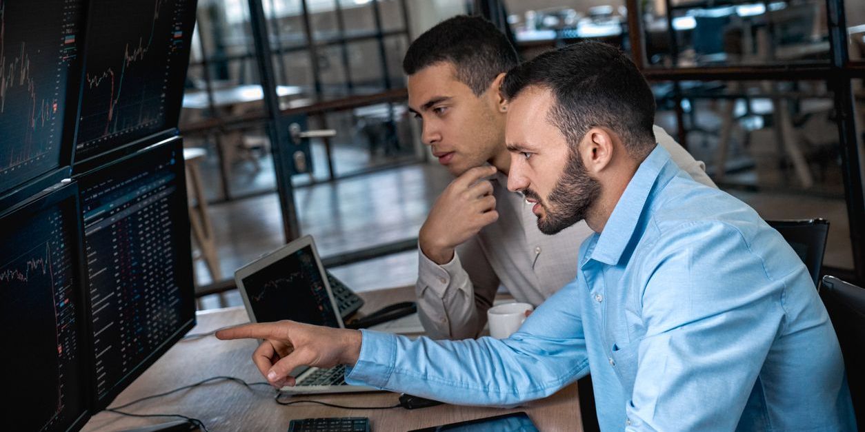 Two financial analysts studying market data on screens