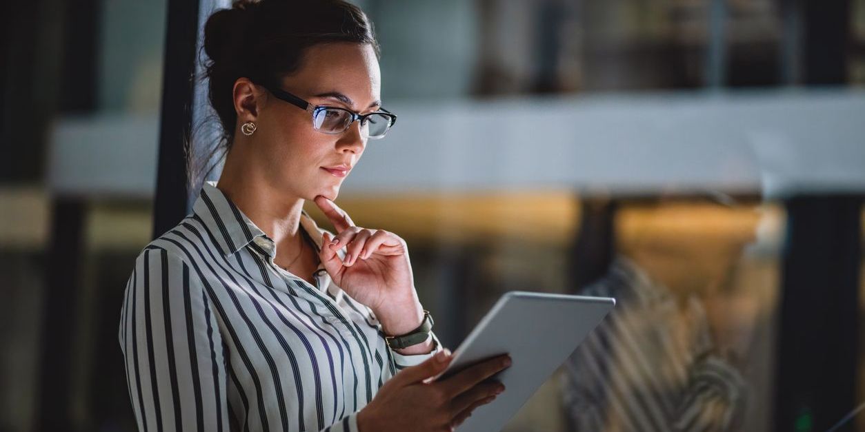 Female financial professional looking at tablet near an office window